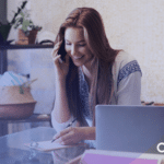 Gen Z employee smiling on phone call taking notes